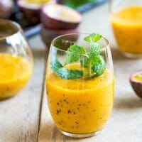 A tropical fruit smoothie with a passionfruit on the side served with Crushed Ice.