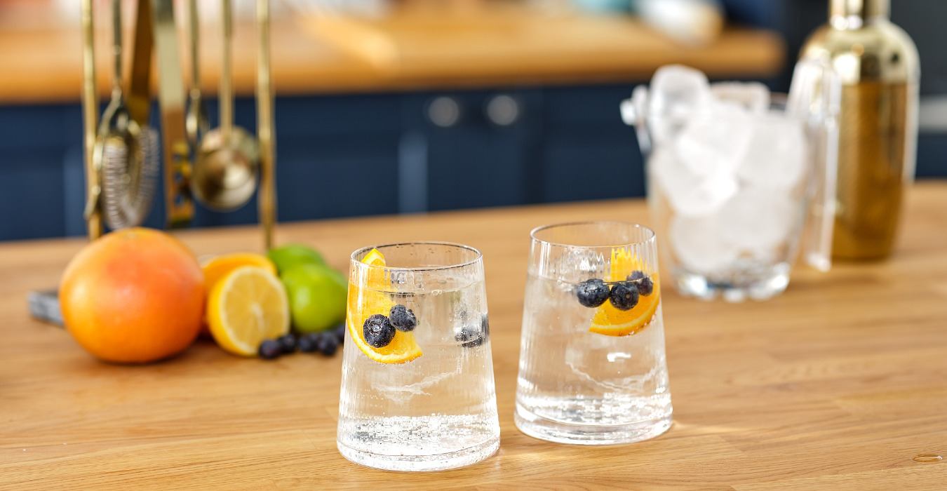 2 gin and tonics garnishes with blueberries and orange wedge