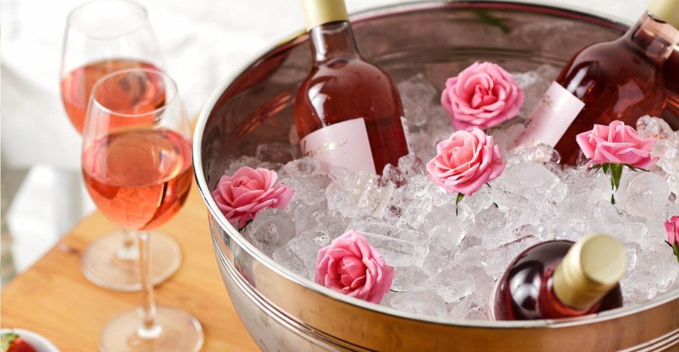 Large ice bucket filled with ice, rose wine and flowers