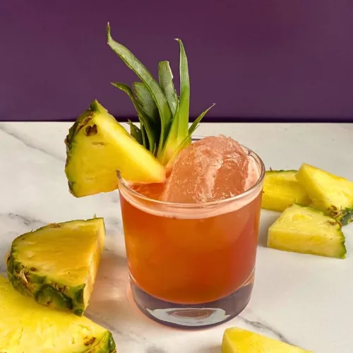 tropical red cocktail in a short glass with pineapple slices