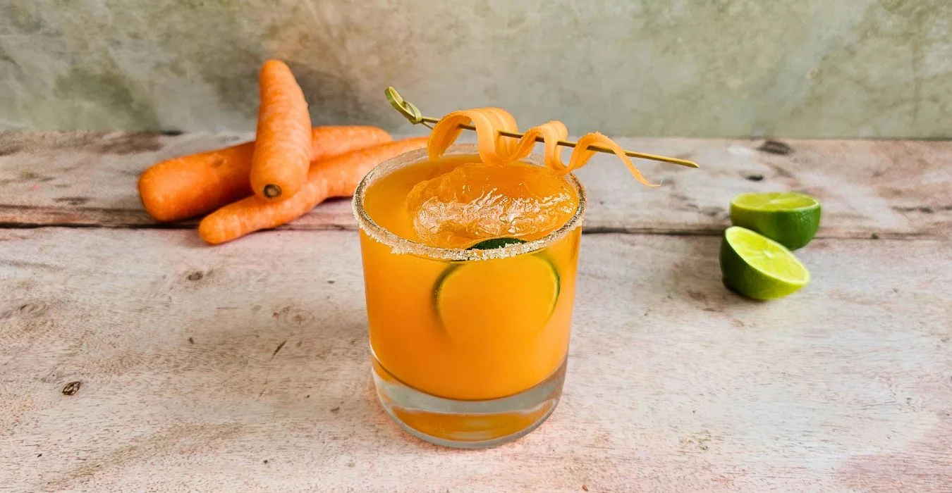 bright orange carrot margarita cocktail on a wooden table