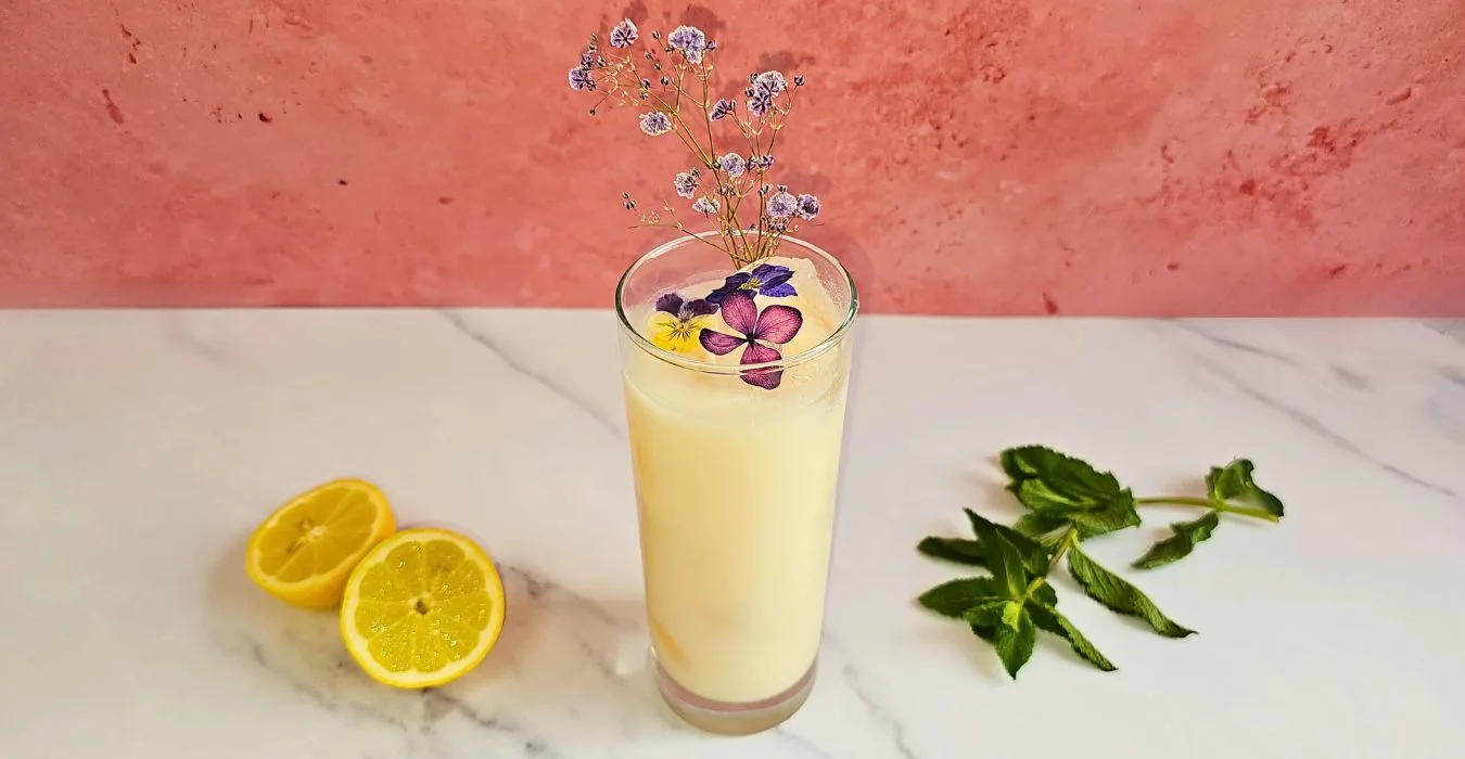 white creamy cocktail with edible flowers on a marble counter