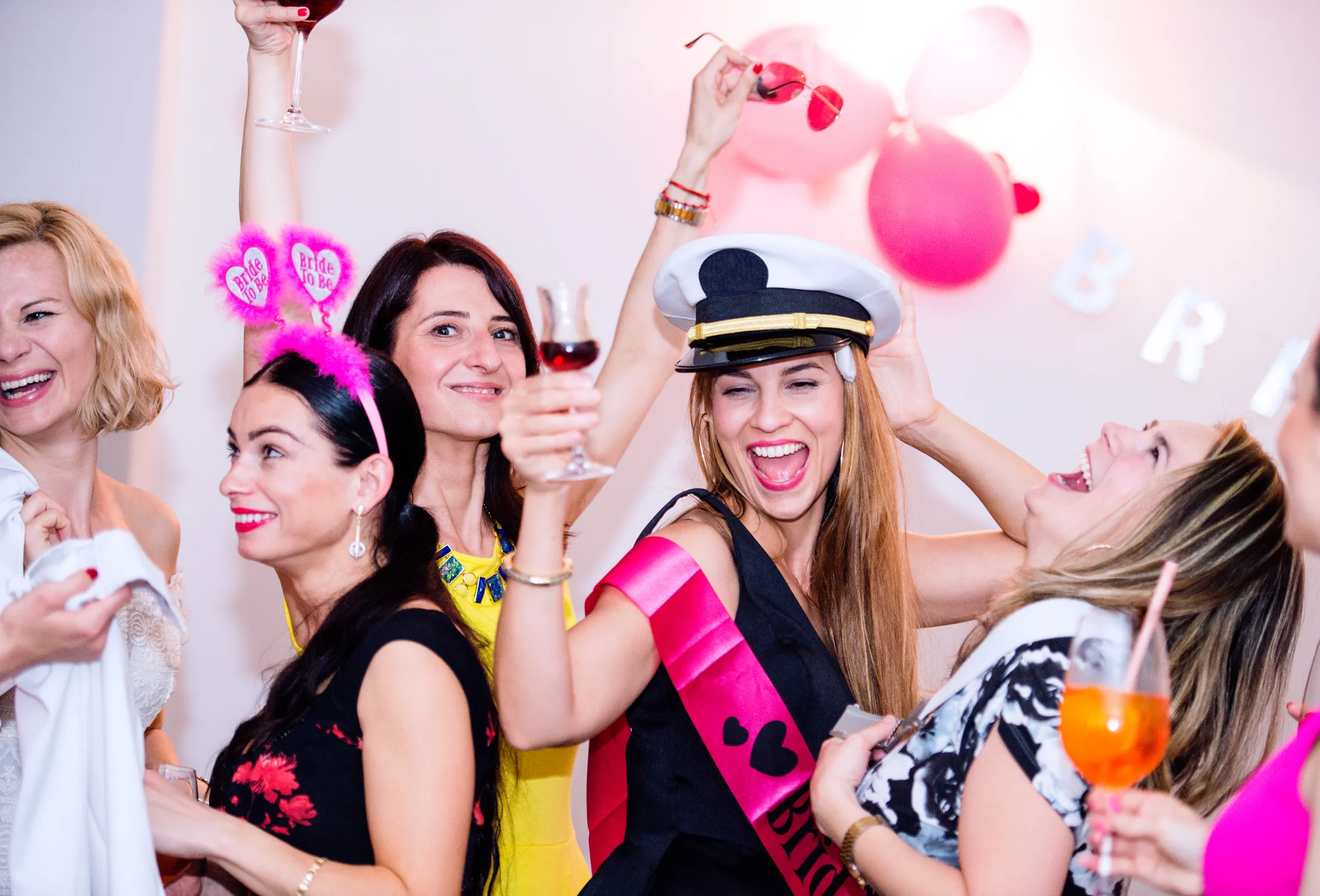 Cheerful bride and happy bridesmaids celebrating hen party with drinks. Women enjoying a bachelorette party dancing.