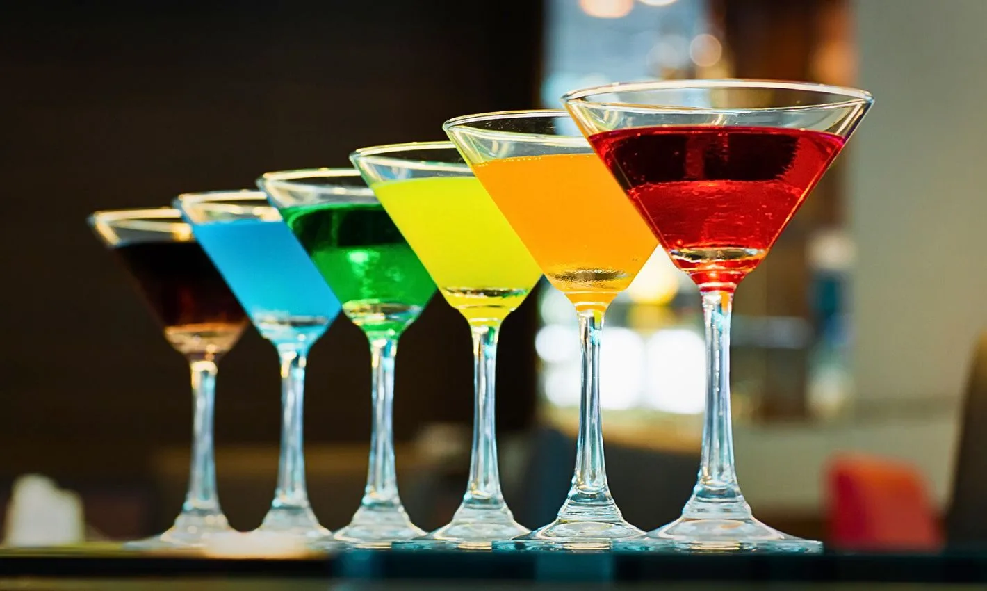 rainbow martini cocktails lined up on a bar