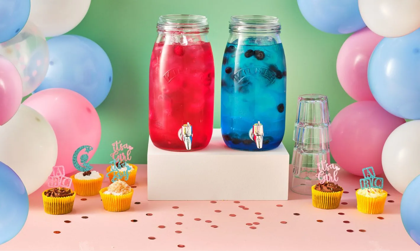 kilner jars filledd with pink or blue cocktails for a baby shower, surrounded by balloons and cupcakes