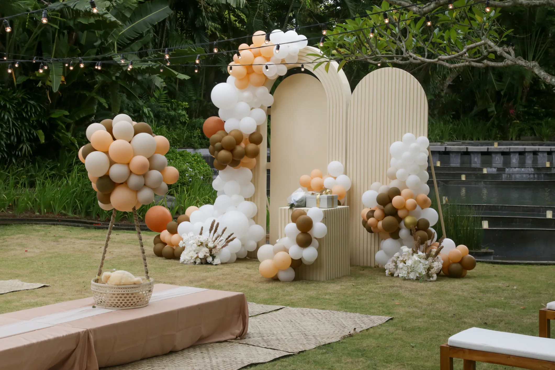 Creative baby shower or decoration in the garden. Bohemian style outdoor event set up with balloons. White cream peach caramel balloon arch kit.