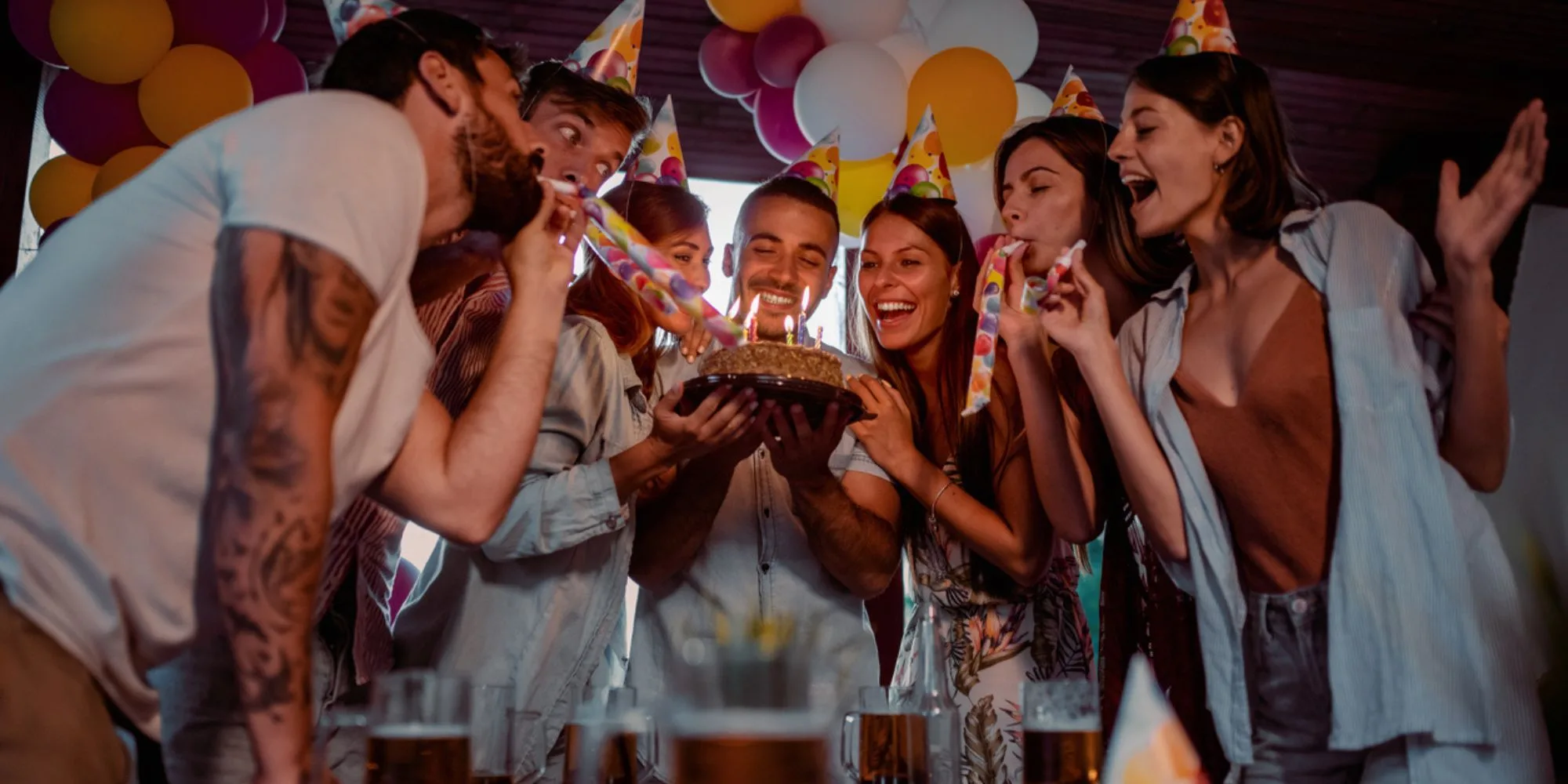 friends help the birthday boy blow out the candles on his cake