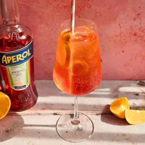 camperol spritz cocktail next to bottles of campari and aperol