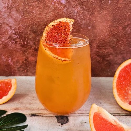 spicy paloma shandy cocktail surrounded by red grapefruits