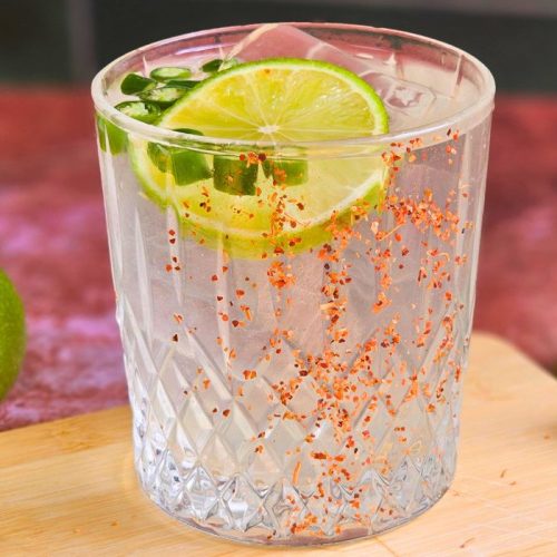 Spicy Margarita Mocktail surrounded with limes in background