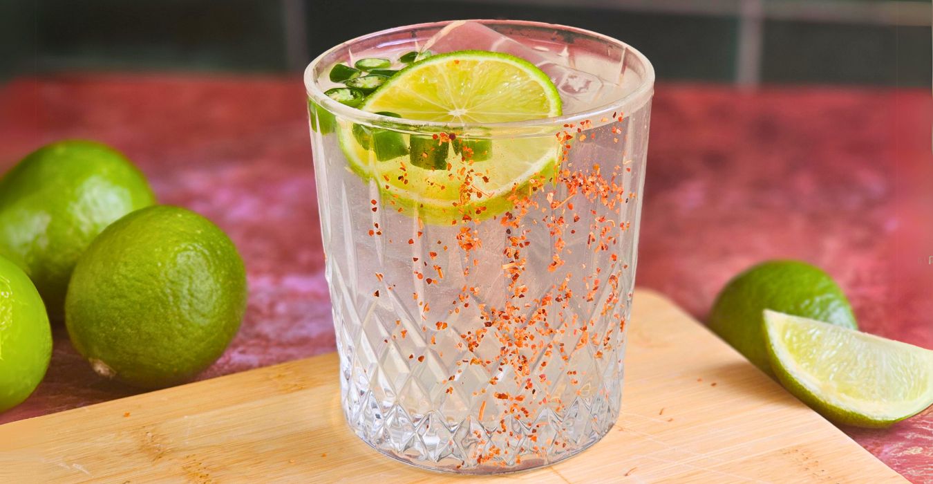 Spicy Margarita Mocktail surrounded with limes in background