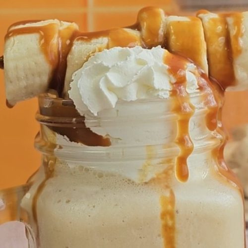 Close up of Banoffee Milkshake, topped with chopped banana and toffee sauce