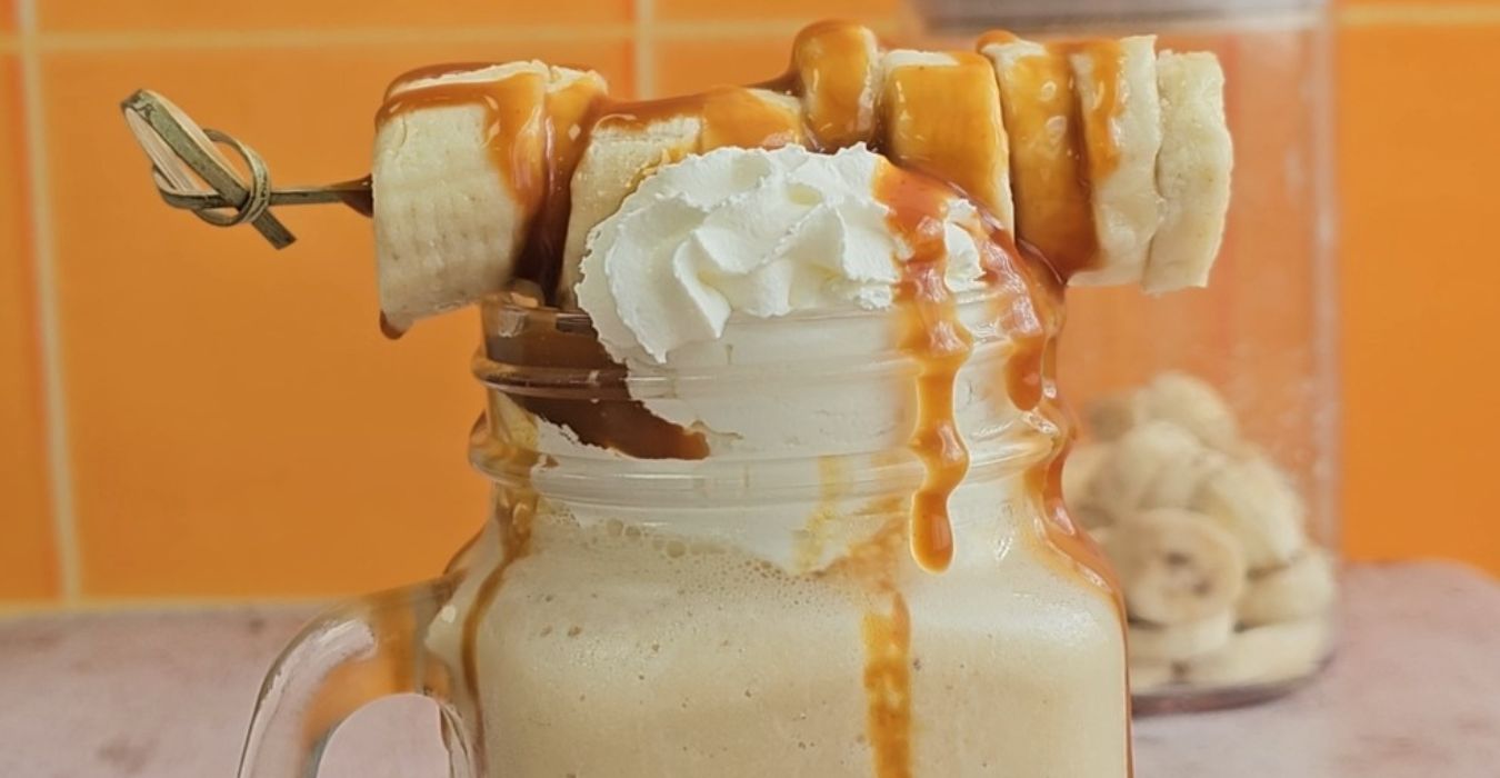 Close up of Banoffee Milkshake, topped with chopped banana and toffee sauce
