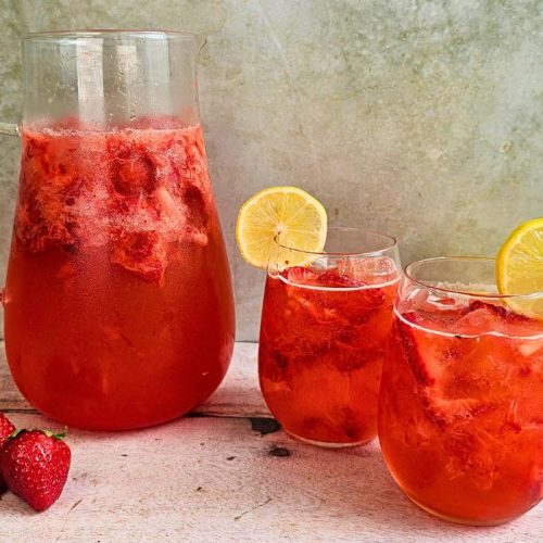 a pitcher and two glasses of sour strawberry spritz summer cocktail