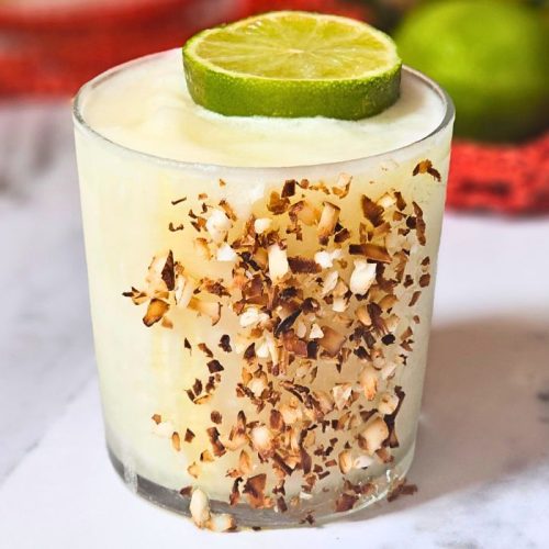 Frozen Pina Margarita cocktail with shredded coconut on the glass and a lime slice