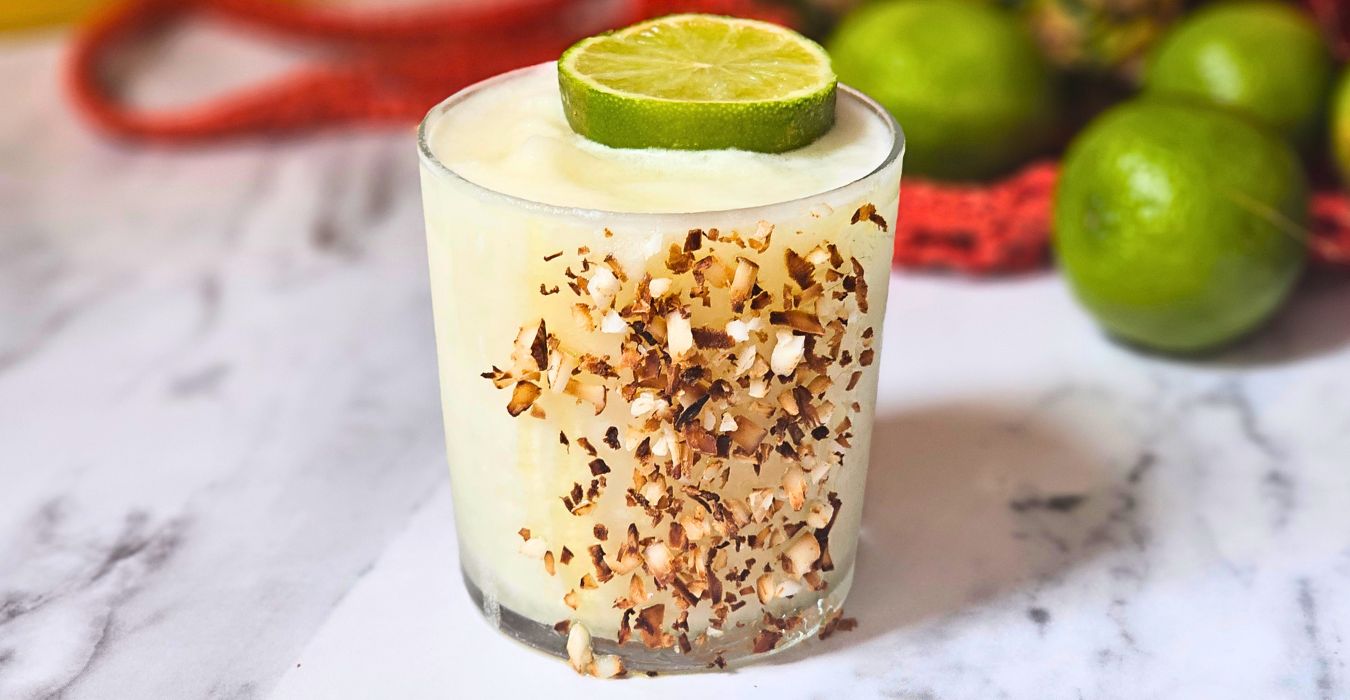 Frozen Pina Margarita cocktail with shredded coconut on the glass and a lime slice