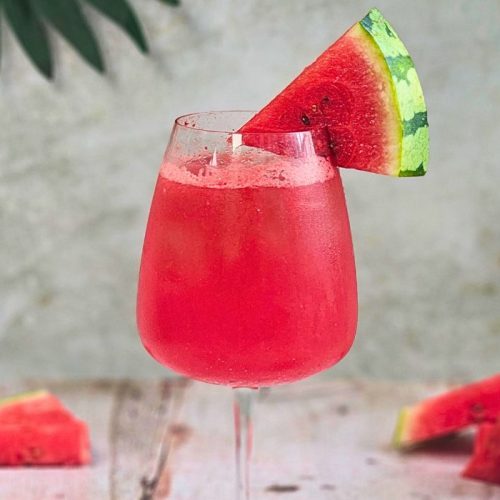 watermelon campari spritz cocktail in a large wine glass with watermelon wedge garnish