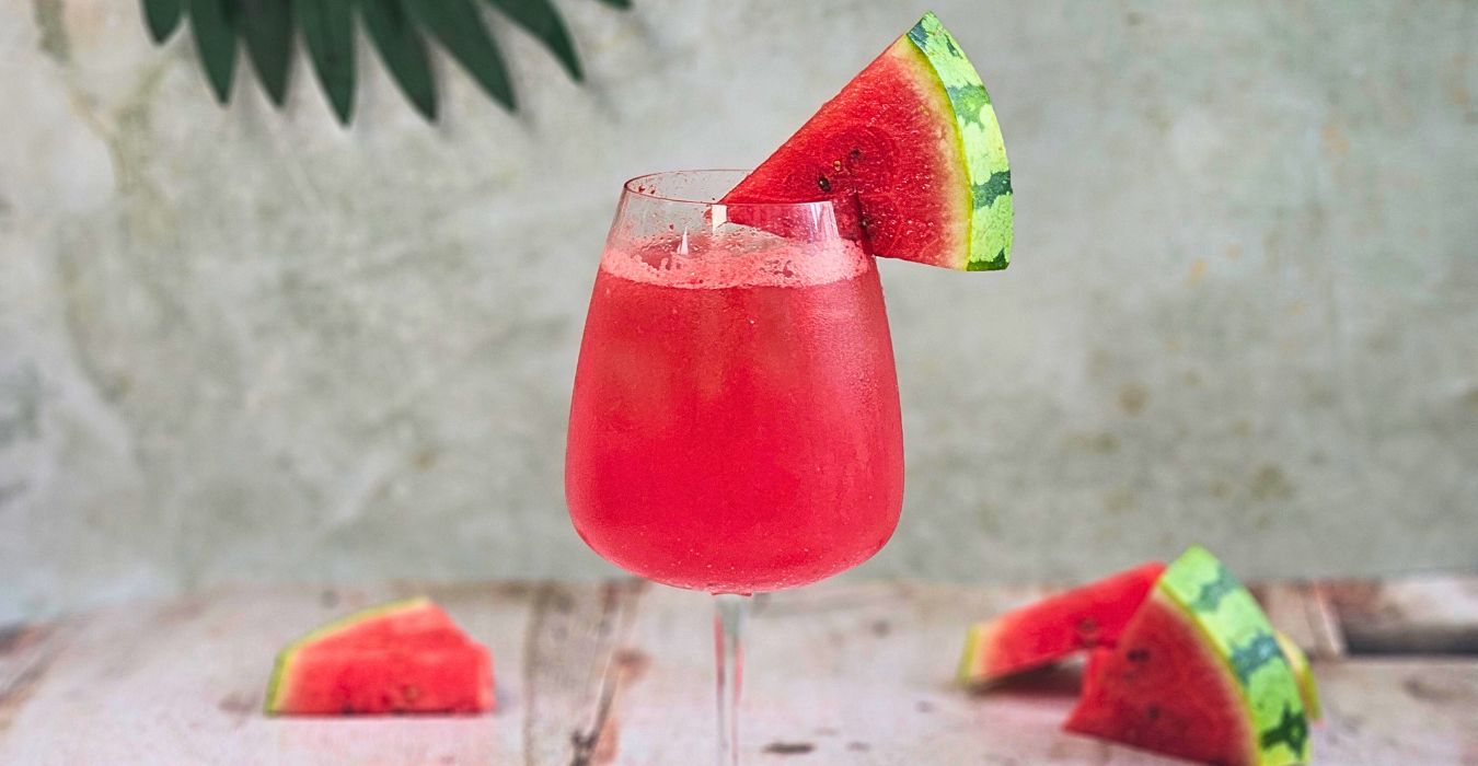 watermelon campari spritz cocktail in a large wine glass with watermelon wedge garnish