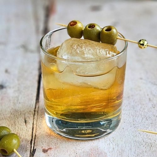 COconut Mezcal Spritz Cocktail Recipe garnished with stuffed olives in a rocks glass