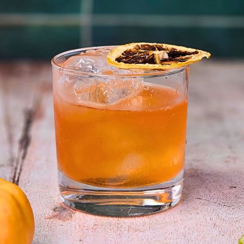 aperol pumpkin spice margarita cocktail in a short glass with tiny pumpkins