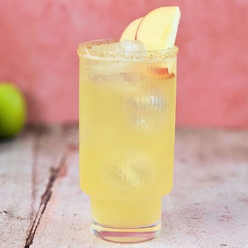 apple cider fizz mocktail cocktail in a tall glas with fresh apple and a sugar rim