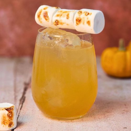 campfire mule cocktail with blackened marshmallows and small pumpkinsin the background