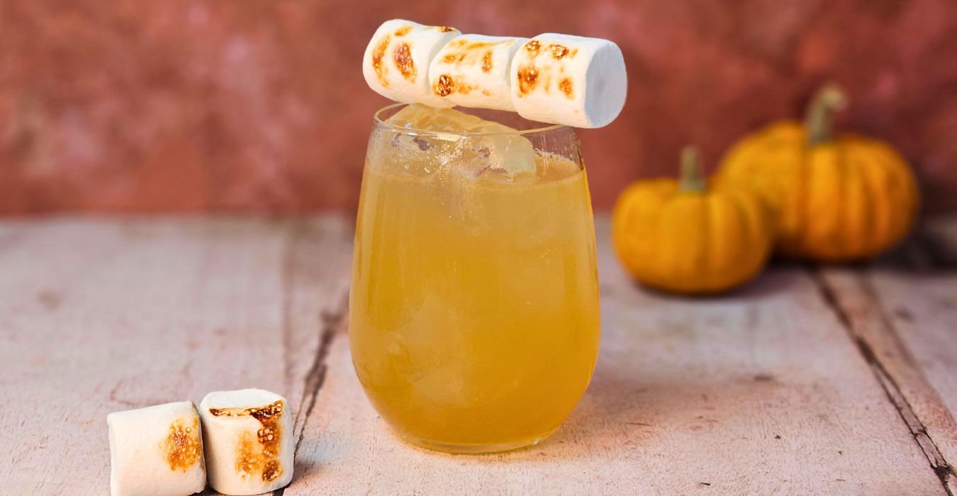 campfire mule cocktail with blackened marshmallows and small pumpkinsin the background